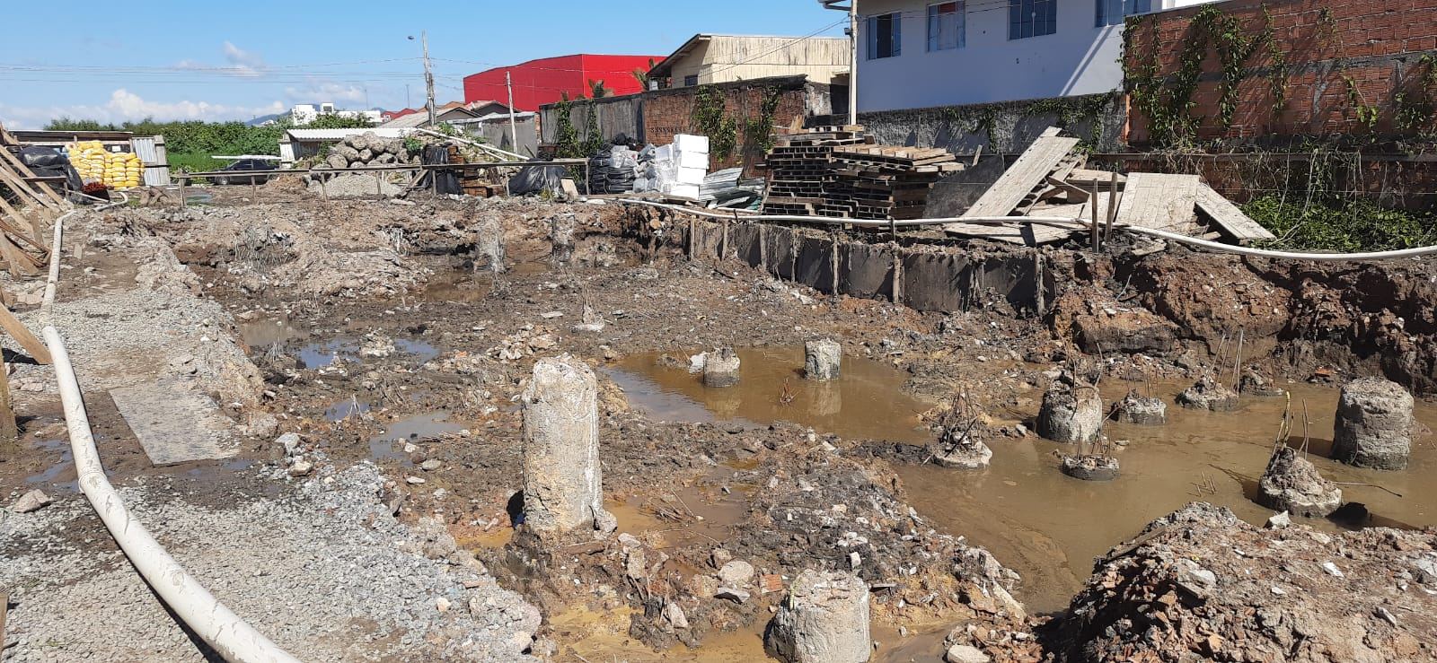 Escavação de fundação em terreno com nível d'água raso e solo mole, estacas parcialmente submersas